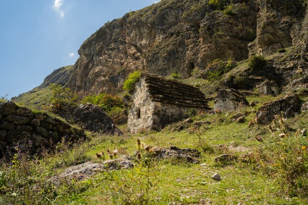 Anciennes maisons en pierre dans les montagnes verdoyantes Paysage étonnant avec des bâtiments en pierre âgés situés sur la pente herbeuse verte de la montagne rocheuse en journée d'été ensoleillée