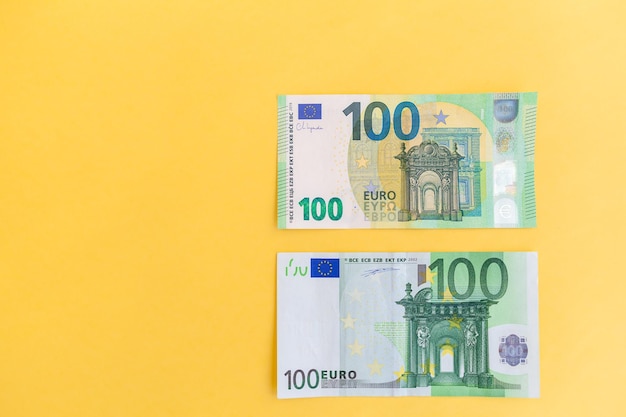 Anciens et nouveaux billets de cent euros sur fond jaune