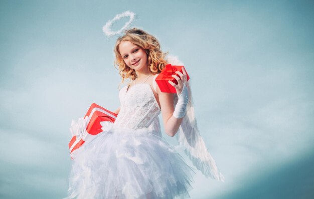 Ange enfant fille aux cheveux blonds bouclés concept d'enfant innocent belle fille cupidon ange avec cadeau