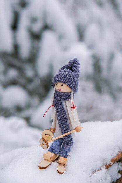 Ange gnome en écharpe et bonnet tricoté skiant sur une branche de sapin enneigé Jouet elfe sur des skis dans un paysage enneigé