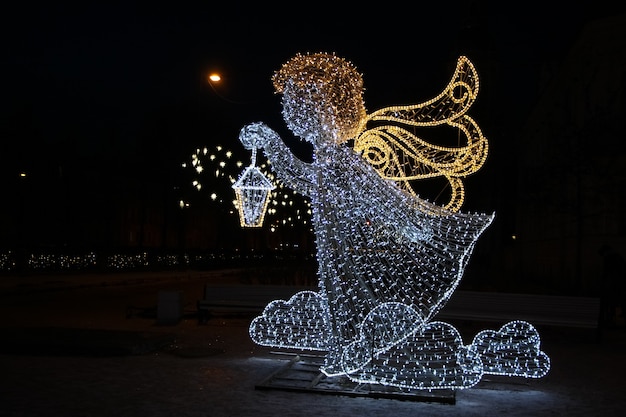 Ange avec une lanterne de guirlandes lumineuses dans un parc de la ville Décoration de Noël