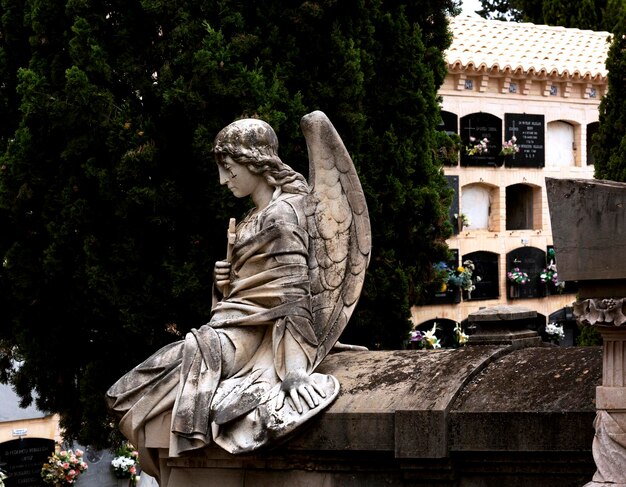 ange tenant une croix assis sur la tombe