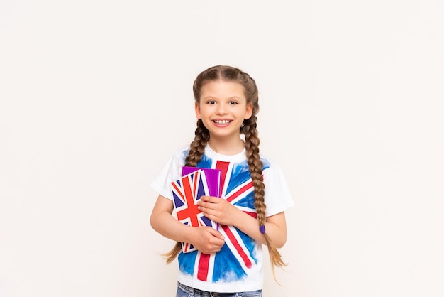 Anglais pour enfants Une petite fille tient un livre sur la langue anglaise avec un drapeau britannique