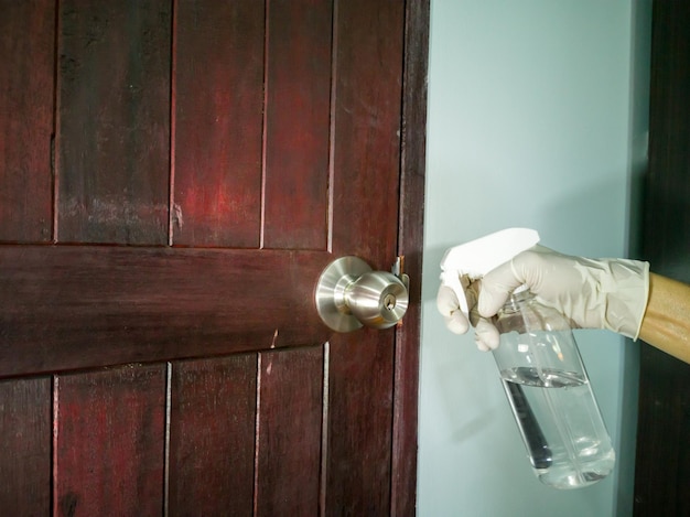 Photo angle au niveau des yeux, nettoyer la poignée de porte en acier inoxydable (porte en bois) à l'aide d'un chiffon de nettoyage