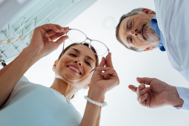 Angle bas d'une belle femme positive debout près de l'opticien