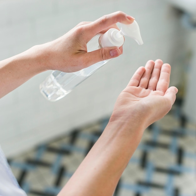 Angle élevé de la personne utilisant un désinfectant pour les mains