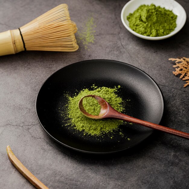 Angle élevé de poudre de thé matcha sur assiette avec une cuillère en bois