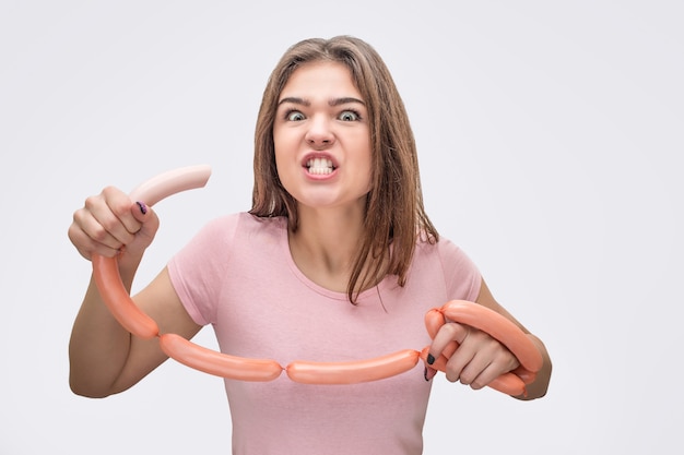 Angry young woman look on camera avec saucisse