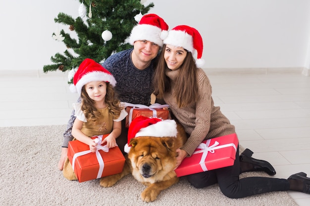 Animal de compagnie, vacances et concept festif - Une famille avec un chien est allongée sur le sol près de l'arbre de Noël.
