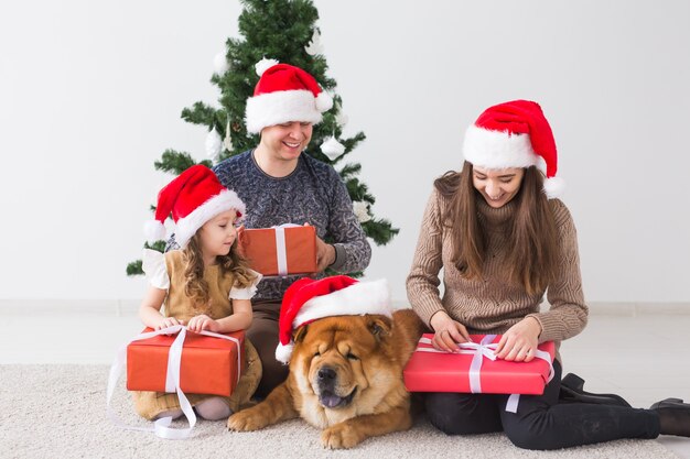 Animal de compagnie, vacances et concept festif - Une famille avec un chien est assise sur le sol près de l'arbre de Noël.