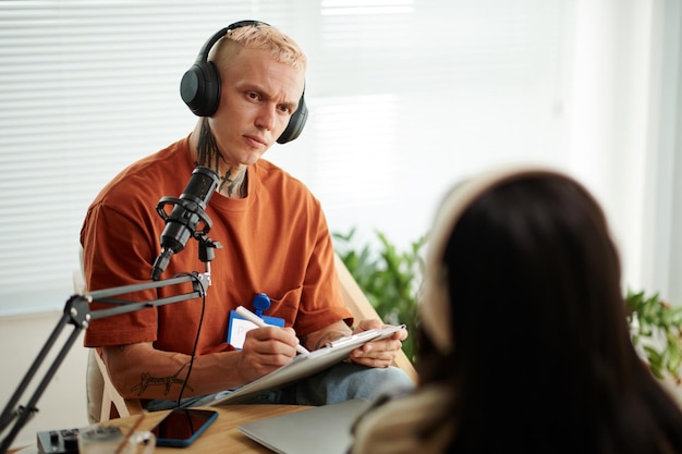 Animateur de radio prenant des notes lorsqu'il parle à l'invité d'un talk-show