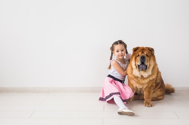 Animaux, enfants et concept d'amitié - petite fille étreignant son chien chow-chow sur un espace blanc