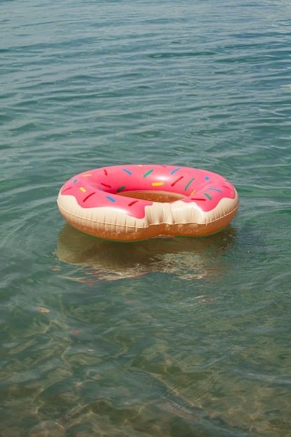 Un anneau de bain gonflable en forme de beignet rose flotte dans l'eau