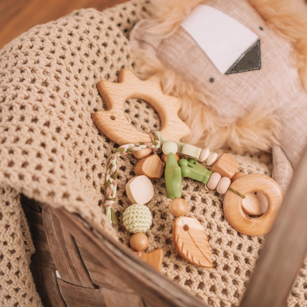 Anneau de dentition en bois pour enfants en forme de hérisson avec des perles en silicone sur une couverture beige dans un panier avec une peluche. Cadre carré