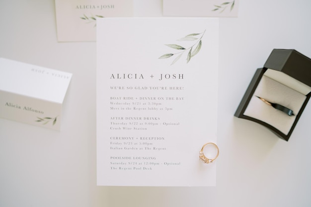 L'anneau de fiançailles se trouve sur une invitation de mariage à côté d'une boîte et de cartes de nom