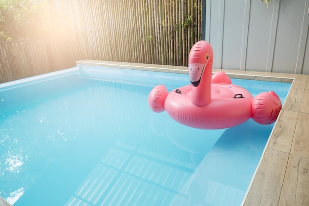 Anneau gonflable rose en plastique flamant rose dans l'eau bleue de la piscine