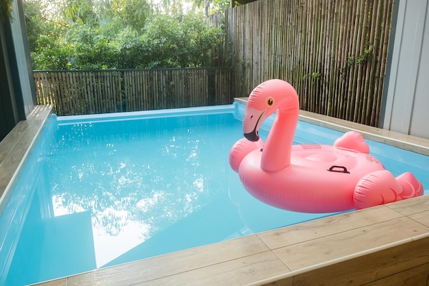 Anneau gonflable rose en plastique flamant rose dans l'eau bleue de la piscine