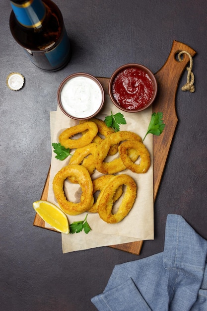 Anneaux de calamars frits aux deux sauces, citron et herbes. Fast food. Apéritif.