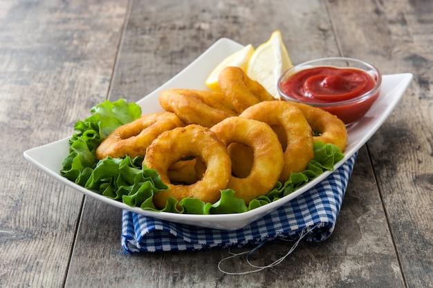 Anneaux de calamars frits avec de la laitue et du ketchup sur une surface en bois