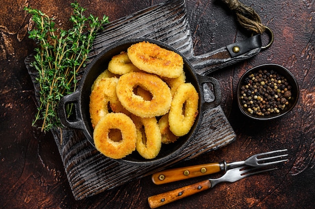 Anneaux de calmar frit panés sur une planche à découper