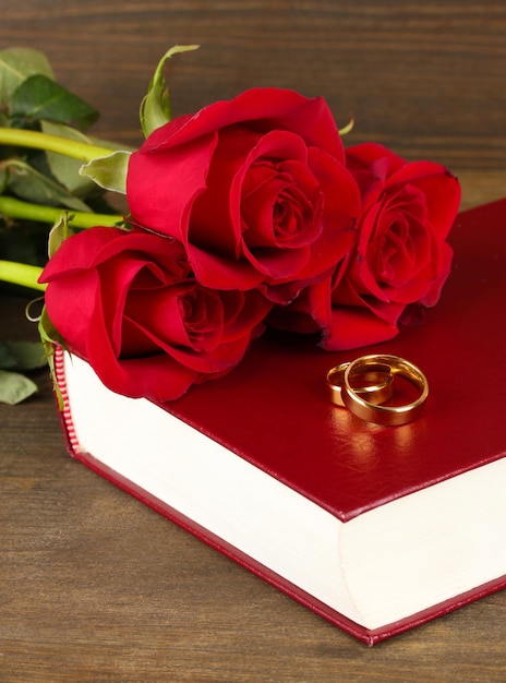 Anneaux de mariage sur la bible avec des roses sur fond de bois