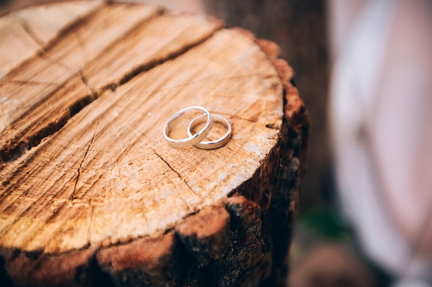 Photo anneaux de mariage. bijoux en or blanc et jaune. bague de mariage sur la texture en bois. talon en bois