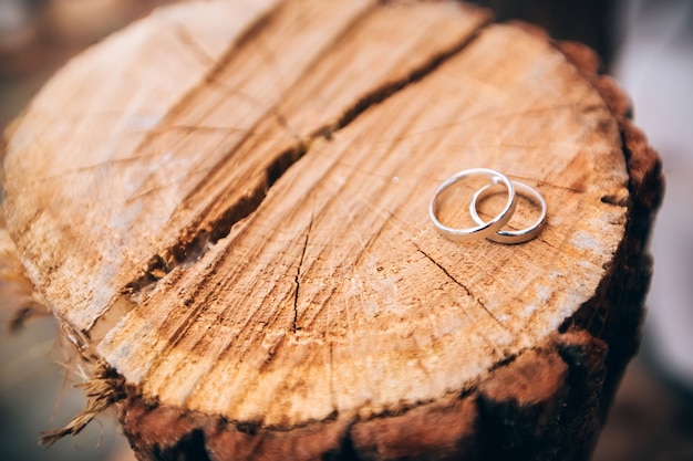 Anneaux de mariage. bijoux en or blanc et jaune. Bague de mariage sur la texture en bois. talon en bois