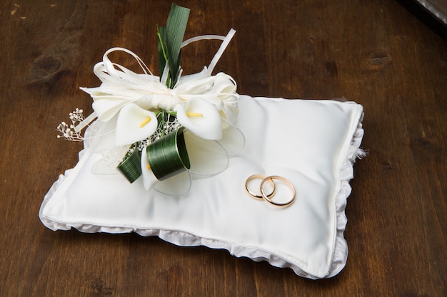 Anneaux de mariage avec bouquet de calla sur table en bois