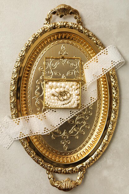 Photo anneaux de mariage dans une boîte à bijoux avec perles sur plateau doré sur fond beige vue de dessus