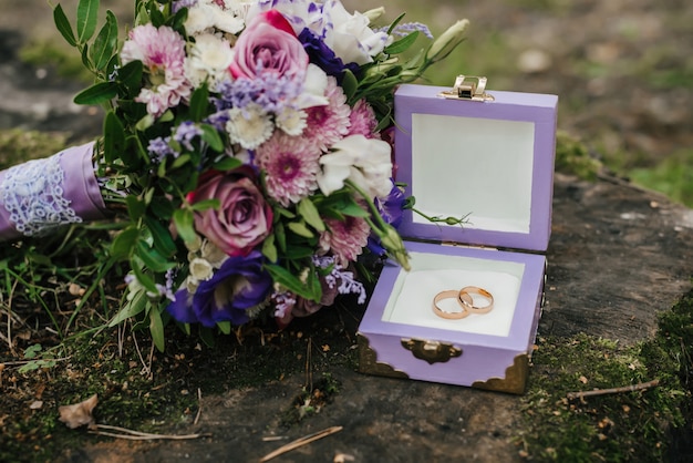 Anneaux de mariage dans une boîte à côté du bouquet