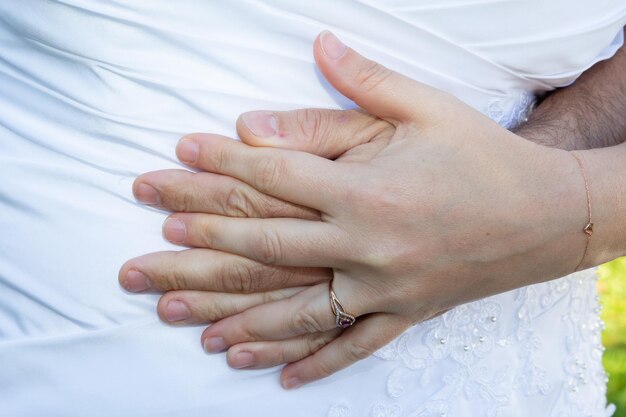 Anneaux de mariage doigts sur couple mariage mariée marié mains sur fond de robe blanche