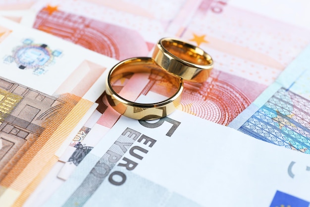 Anneaux de mariage dorés sur fond de billets en euros Mariage de complaisance