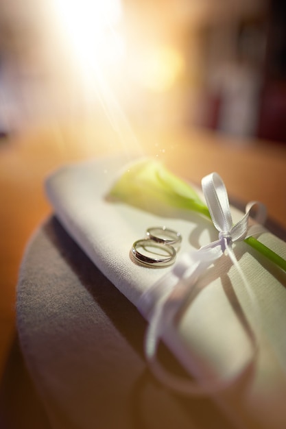 Les anneaux de mariage avec une fleur se trouvent sur une serviette attachée avec un ruban