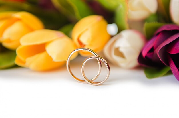 Anneaux de mariage et fleurs isolés sur fond blanc