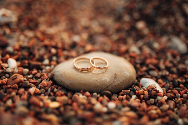 Anneaux de mariage de jeunes mariés sur des galets de plage