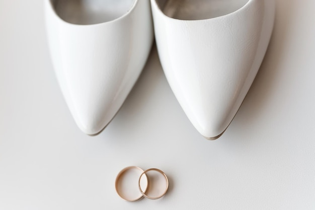 Anneaux de mariage en or classique et chaussures de mariée en cuir verni blanc gros plan Détails de mariage