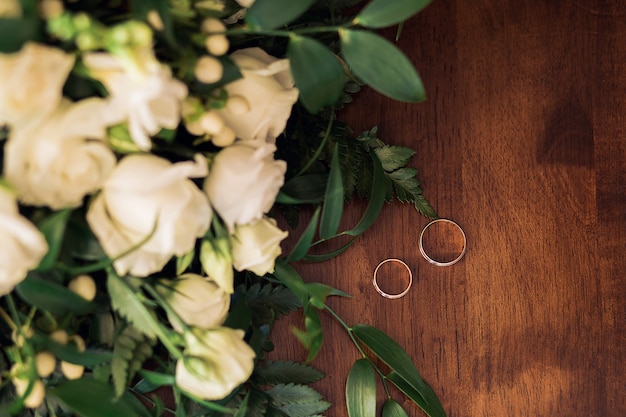 Anneaux de mariage d'or sur un fond en bois avec bouquet de fleurs