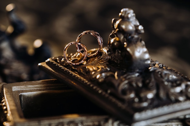 Photo les anneaux de mariage en or reposent sur une boîte à bijoux ancienne. anneaux de mariage pour les cérémonies.