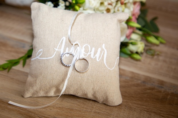 Anneaux de mariage sur un oreiller avec ruban sur une table en bois avec amour texte signifie amour en français