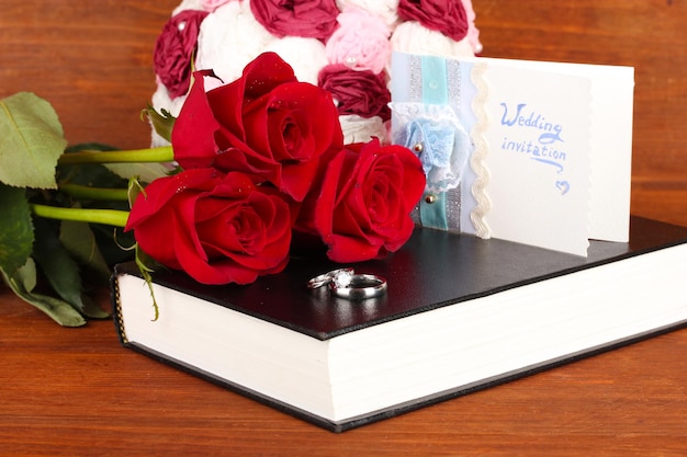 Photo anneaux de mariage avec des roses sur la bible sur fond de bois