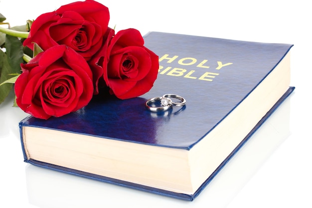 Anneaux de mariage avec des roses sur bible isolated on white