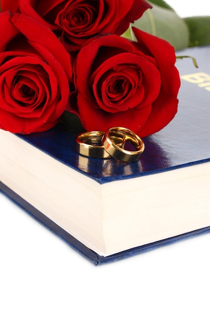 Anneaux de mariage avec des roses sur bible isolated on white