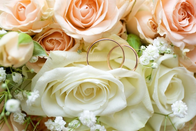 Les anneaux de mariage se trouvent sur des fleurs roses dans un bouquet