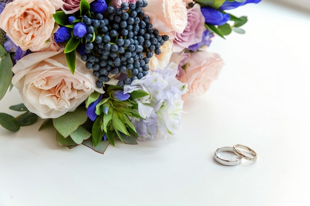 Les Anneaux De Mariage Se Trouvent Sur Une Surface En Bois Sur Fond De Bouquet De Fleurs