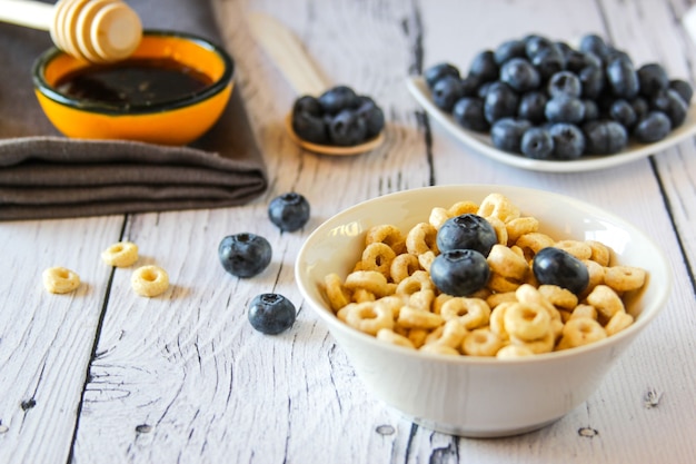 Anneaux de miel avec des myrtilles et du miel dans un bol sur le fond en bois de la table Petit-déjeuner sain