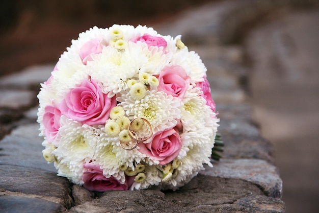 Anneaux d'or de mariage avec bouquet de fleurs de mariée