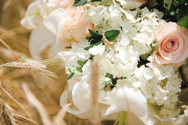 Anneaux d'or de mariage sur un bouquet. Jour de mariage. Bouquet de mariée dans un champ de blé