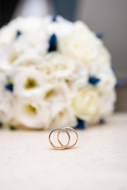 Anneaux d'or de mariage sur le fond d'un grand bouquet sur la table de vacances des jeunes mariés