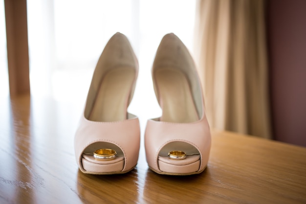 Anneaux d'or de mariage à l'intérieur des chaussures roses de la mariée. La cérémonie