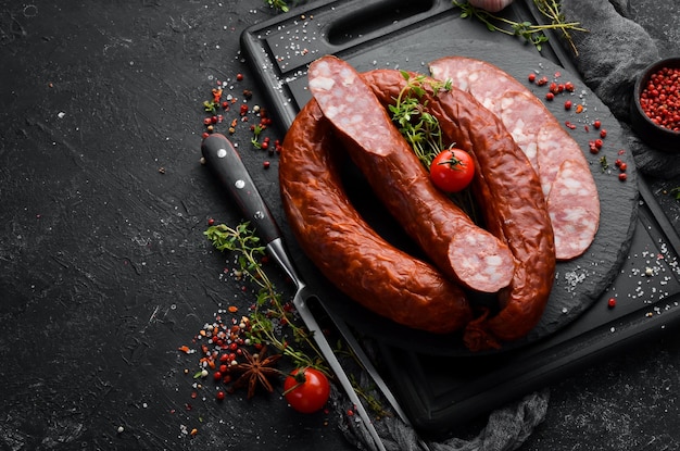 Anneaux de saucisse fumée traditionnelle dans une composition de style campagnard sur fond de pierre noire Vue de dessus Espace libre pour le texte